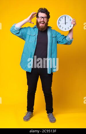 In voller Länge Foto von verrückten bärtigen Mann mit großen Wanduhr. Stockfoto