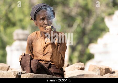 Sagaing/Myanmar-3. Oktober 2019: Eine burmesische ältere Frau raucht eine mit Blättern umwickelte Zigarette und hat Tabak im Inneren. Stockfoto