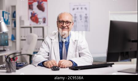 Porträt eines im Krankenhausschrank lächelnden Oberarztes, der die Kamera anschaut. Stockfoto