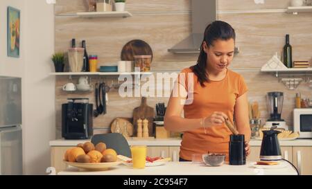 Frau, die Kaffeebohnen in die Mühle am Morgen. Hausfrau zu Hause, die frisch gemahlenen Kaffee in der Küche zum Frühstück, Trinken, Kaffeemühlen Espresso vor der Arbeit Stockfoto