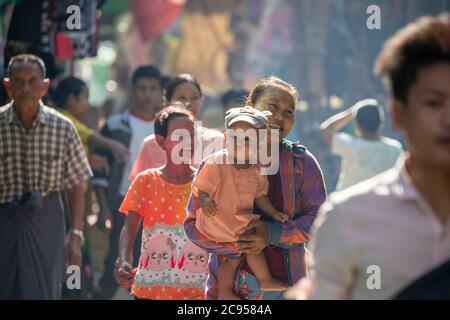 Sagaing/Myanmar-3. Oktober 2019: Ein burmesisches Kind wurde von der Mutter getragen, um auf dem Morgenmarkt zu spazieren. Stockfoto