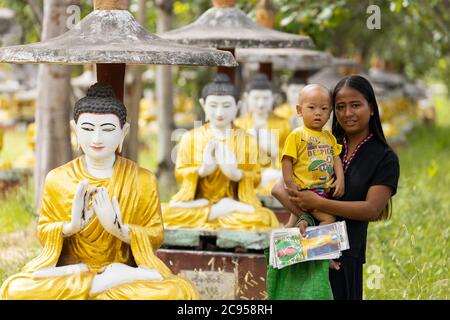 Sagaing/Myanmar-3. Oktober 2019: Eine burmesische Frau hält ihr Kind in einem Tempel in der Warteschlange, um Gemälde an Touristen zu verkaufen. Stockfoto