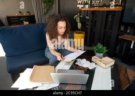 Lächelnd schöner junger bärtiger Mann in Denim-Hemd, der auf einem modernen Laptop während der Arbeit im Café tippt Stockfoto