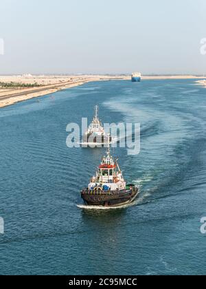 El Qantara, Ägypten - 14. November 2019: Schlepper begleiten die Schiffe. Schiffe, die durch den Suezkanal in Ägypten, Afrika, fahren. Stockfoto