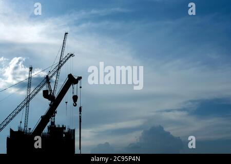 Silhouette im Bau Hochhaus Eigentumswohnung Gebäude Immobilien-Industrie mit Hebezeugen Kräne in blauen Morgenhimmel. Immobilien und c Stockfoto