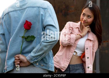Junge glückliche Paare lieben und romantisch auf den ersten Tag Beziehung: asiatische Teenager-Frau überrascht und lächelt an Freund gibt rote Rosen-Blumen auf Dinne Stockfoto