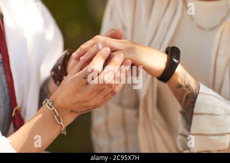 Nahaufnahme einer Frau, die Ring auf den Finger ihrer Freundin legt, sind sie verlobt Stockfoto