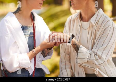 Zwei junge Lesben sind verlobt, sie legen Ringe an den Fingern zueinander Stockfoto