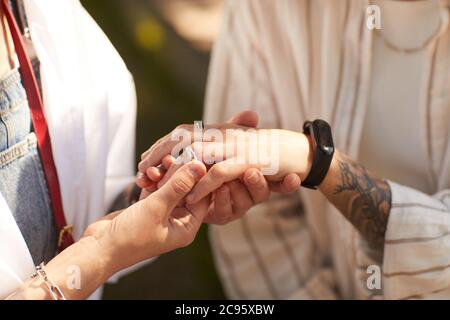 Nahaufnahme einer Frau, die den Ring an den Finger ihrer Freundin legt und ihr einen Vorschlag macht Stockfoto