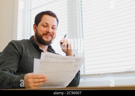 Büromitarbeiter füllt Dokumente im Schrank, hält Papiere und Stift. Stockfoto