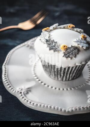 Geburtstag dekorierte Cupcake und goldene Gabel auf weißem Teller und dunkel verschwommen Hintergrund. Stockfoto