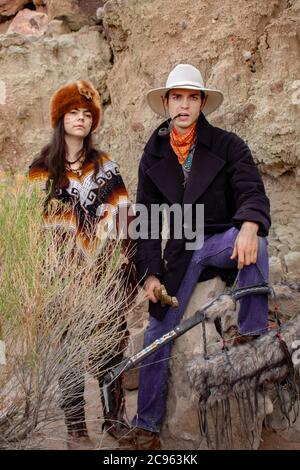 Ein Pelzfellfänger mit Poncho und Pelzhut und ein Cowboy mit Bogen und Tabakpfeife in einer trockenen Wüstenschlucht in der ojito Wilderness Area in New Mexico Stockfoto