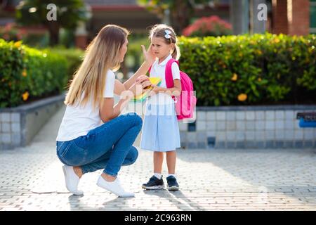 Mutter und Kinder nach der Schule. Junge Mutter, die Kinder nach dem Unterricht im Kindergarten oder in der Vorschule abholt. Holt Schüler ab. Junge und Mädchen laufen zu pare Stockfoto