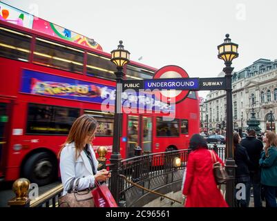London, Großbritannien - Piccadilly Circus. Straßenszene am Eingang zur U-Bahn. Eine junge Frau spricht auf ihrem Handy. London, Gr Stockfoto