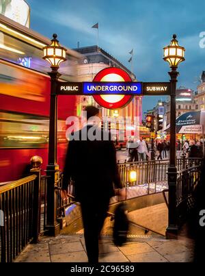 London, Großbritannien - Piccadilly Circus. Straßenszene am Eingang zur U-Bahn. Ein Manager in einem schwarzen Anzug mit Aktentasche geht an die Under Stockfoto