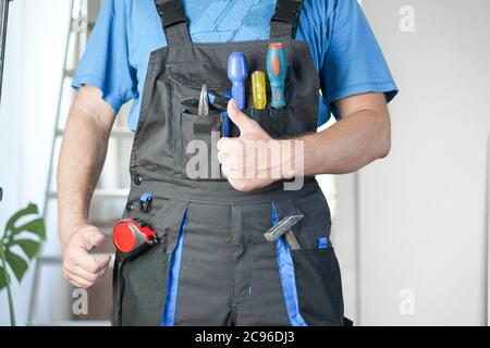 Kerl in Arbeitskleidung zeigt wie Stockfoto
