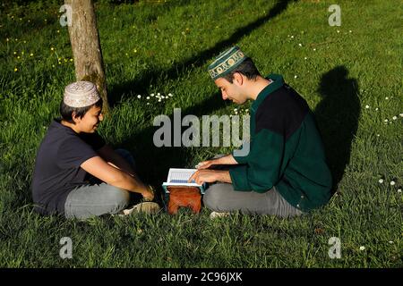 Teenager und junger Mann beim Lesen des Kuran in einem Garten in Frankreich. Stockfoto