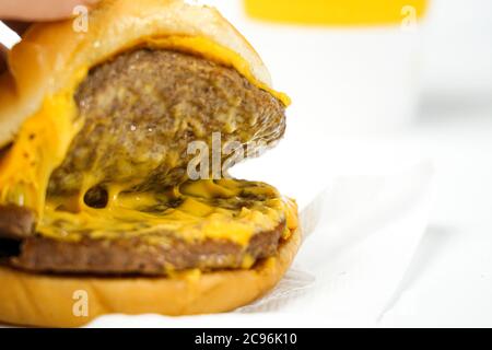 Fleischschnitzel in einer Burger Nahaufnahme auf weißem Hintergrund Stockfoto