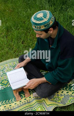 Junger Mann beim Lesen des Kuran in einem Garten in Frankreich. Stockfoto