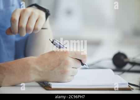 Nahaufnahme des Geschäftsmannes, der Notizen in Notizblock am Tisch macht, an dem er sein Geschäft plant Stockfoto