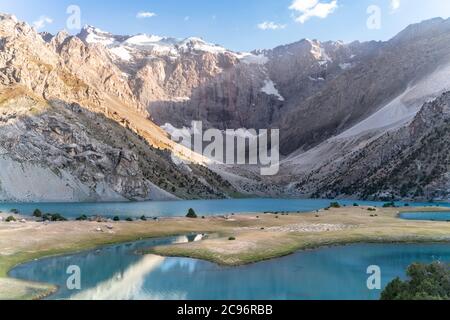 Der Pamir-Bergblick und ruhiger Campingplatz am Kulikalon-See im Fann-Gebirge in Tadschikistan. Aufmunterende bunte Reflexion in reinem Eissee. Stockfoto