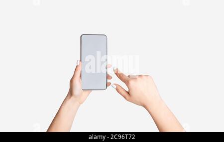 Unerkennbare junge Mädchen zeigt Smartphone mit leerem Bildschirm auf weißem Hintergrund, Mockup für mobile App-Design Stockfoto