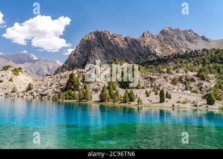 Die schöne Bergwanderstraße mit klarem blauen Himmel und felsigen Hügeln und der Blick auf den Alaudin See in Fann Berge in Tadschikistan Stockfoto
