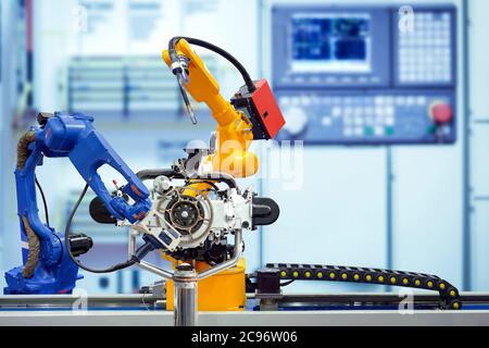 Industrielle Roboter arbeiten mit Motorteilen auf Smart Factory, auf verschwommenem Bedienfeld blauen Ton Hintergrund, Industrie 4.0 Stockfoto