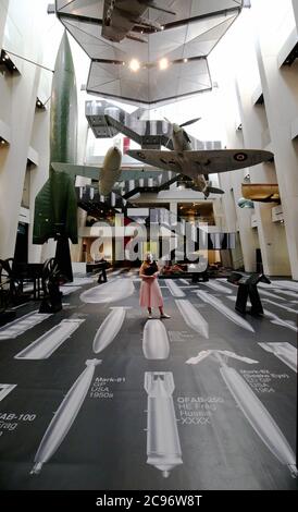 Ein Mitarbeiter des Imperial war Museum steht auf einem Teil der Oberfläche von Ai Weiweis 'Geschichte der Bomben' während einer Fotoausstellung für das neue Werk des chinesischen Künstlers, die im Imperial war Museum in London zu sehen ist. Das Kunstwerk zeigt 50 maßstabsgemaßte Bomben vom Ersten Weltkrieg bis in die Gegenwart und deckt die Böden und Wände des IWM-Atriums auf einer Fläche von über 1,000 Quadratmetern ab. Stockfoto