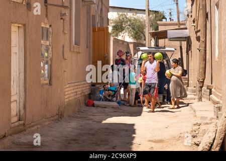 Chiwa/Usbekistan-21.04.2020: Die usbekische Familie und der Mann, der Wassermelone aus dem Auto trägt Stockfoto