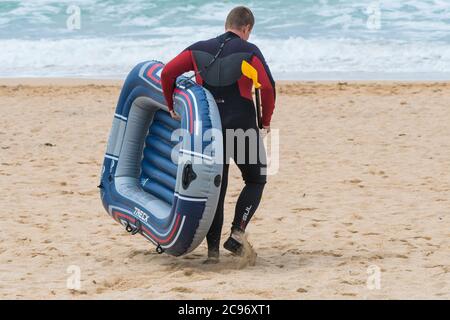 Ein Urlauber mit einem Schlauchboot auf Fistral; Beach in Newquay in Cornwall. Stockfoto