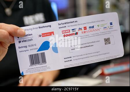 Köln, Deutschland. Juli 2020. Eine Mitarbeiterin in einer Filiale des Händlers REWE hält ein Blatt Papier mit einem Barcode in der Hand. Mit diesem Blatt können Kölner Bürger ihre Parkscheine künftig einfach an Supermarktkassen bezahlen. Quelle: Henning Kaiser/dpa/Alamy Live News Stockfoto