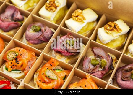 Pappkarton mit Catering-Food-Lieferung vor Ort für Wein-Party.leckere Snacks mit gesunden Zutaten für Buffet auf Veranstaltung vorbereitet.Tasty Red fis Stockfoto