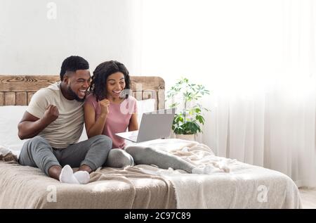 Aufgeregt afrikanischen Paar ausrufen Glück, halten Laptop Stockfoto