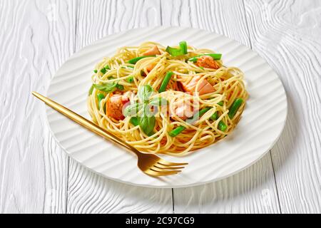 Wild alaska Lachs Pasta mit italienischen Spaghetti, grünen Bohnen und Knoblauchbutter Sauce mit frischem Basilikum auf einem weißen Teller mit Gabel auf einem Whit serviert Stockfoto