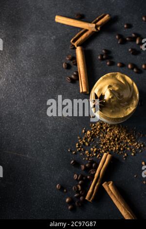 Dalgona Kaffee in einer transparenten Tasse auf dunklem Hintergrund. Südkoreanisches Getränk mit Schlagkaffee, Zucker und Milch. Stockfoto