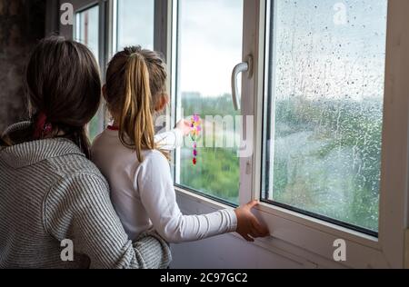 Mutter und Tochter schauen bei Regenwetter aus dem Fenster Stockfoto