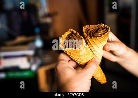 Waferrollen mit Kondensmilch werden in Händen gehalten. Kuchen Süßigkeiten Stockfoto