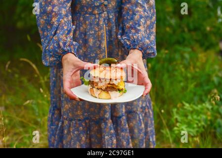 Saftiger Burger in den Händen. Hand hält einen leckeren Fast Food Cheeseburger. Das Konzept der Fast Food. Leckere ungesunde Burger Stockfoto