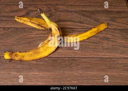 Bananenschale einer überreifen Banane auf braunem Holzhintergrund. Stockfoto