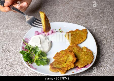 Kartoffelpfannkuchen auf einem Teller, serviert mit saurer Sahne und Petersilie. Stockfoto