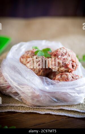 Gefrorene rohe Fleischbällchen aus Rind und Schweinefleisch mit Karotten und Reis in Zellophanbeutel Stockfoto