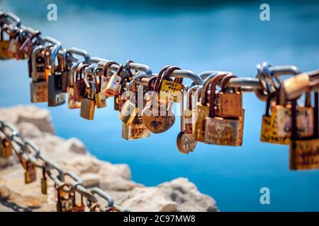 Alte rostige Vorhängeschlösser, die an einem Metallzaun hängen Stockfoto