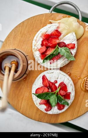 Gegrillter Camembert-Käse mit Erdbeere, Honig und Basilikumblättern, Delikatessen Stockfoto