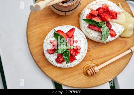 Gegrillter Camembert-Käse mit Erdbeere, Honig und Basilikumblättern, Delikatessen Stockfoto