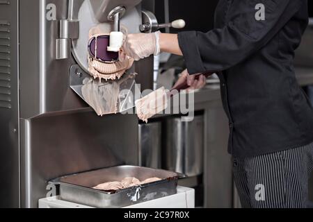 Nougat-Eis aus der Eismaschine in der kleinen Fertigung erhalten - mit einem industriellen Abschaufel aus Edelstahl Stockfoto