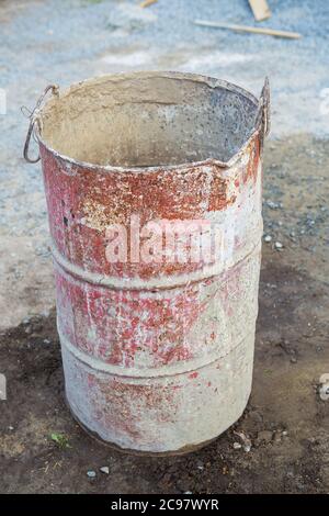 Auf der Straße steht ein altes rostiges Metallfass, das mit bunten Flecken bedeckt ist. Alles für Reparatur, Bau Stockfoto