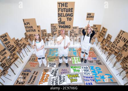 Künstler Peter Liversidge, zusammen mit Mirin Cowey (links) und ihrer Schwester Beth Cowey vom Orbit Youth Council, die ein Sign Painting Studio betreiben, in dem Kunstwerke auf Wunsch zum Mitnehmen im Jupiter Artland, Edinburgh gemalt werden. Die Performance ist Teil von 'Happenings', einer Veranstaltungsreihe, die vom Werk des spätamerikanischen Avantgarde-Künstlers Allan Kaprow (1927-2006) inspiriert ist. Stockfoto