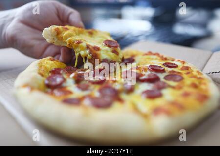 Mann nimmt Pizzablecken mit Wurst Nahaufnahme Stockfoto