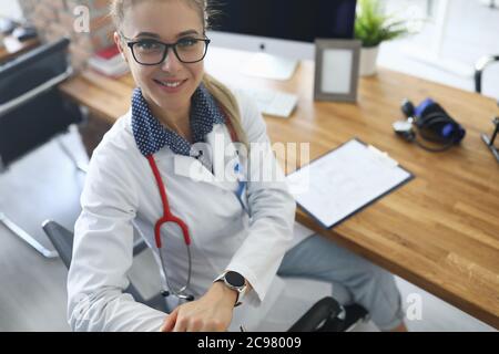 Junge Fachärztin sitzt an einem Tisch in einer Klinik Stockfoto